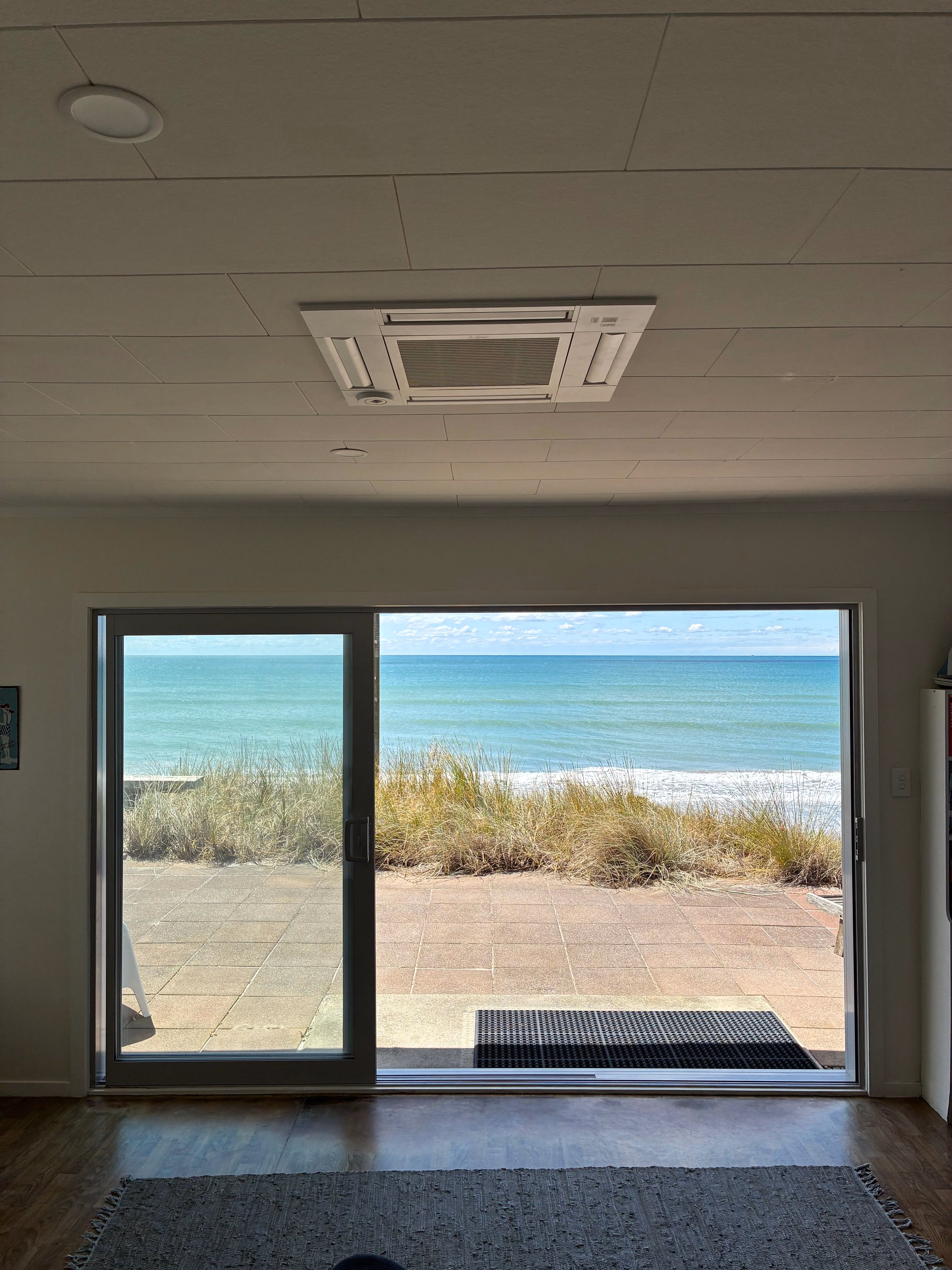 A mitsubishi electric ceiling cassette installed infront of a coastal property in Papamoa