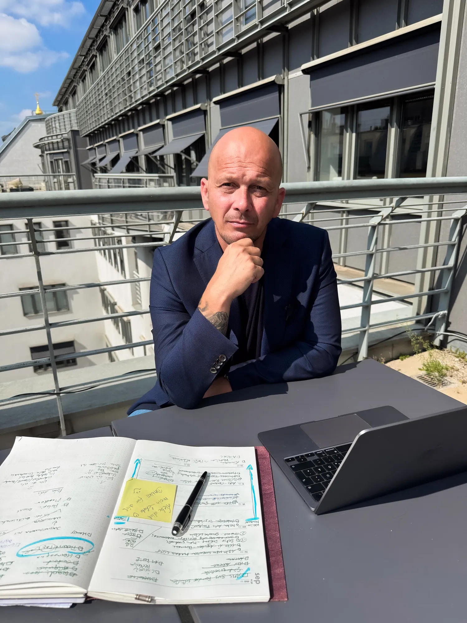 Arnold Freissling mit Laptop und Notizbuch auf einer Dachterrasse