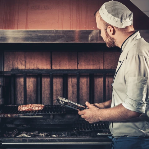 Chef die biefstuk grilt op houtskoolbarbecue als voorbeeld voor beschrijvende alt-tags