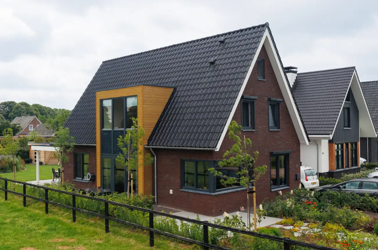 Vrijstaande woning met donkere kozijnen en houten risaliet