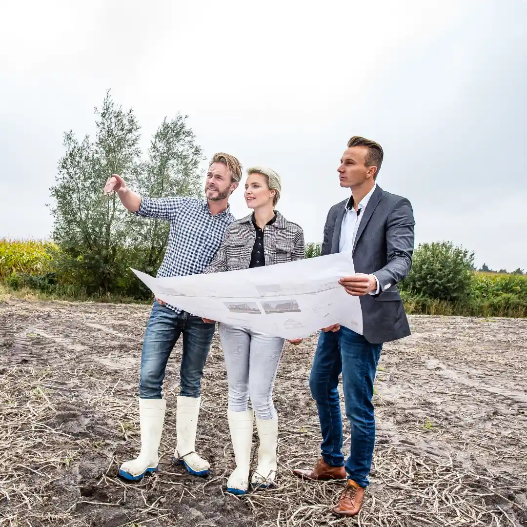 Drie mensen staan in het weiland met een plattegrond in hun hand