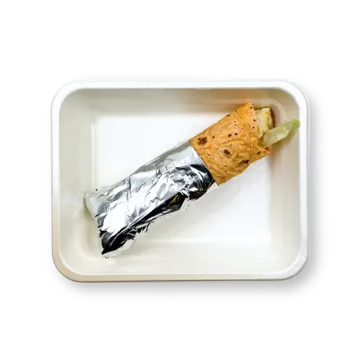 Wrap v hliníkové fólii s kouskem zeleniny v papírovém boxu na jednom jídlo.