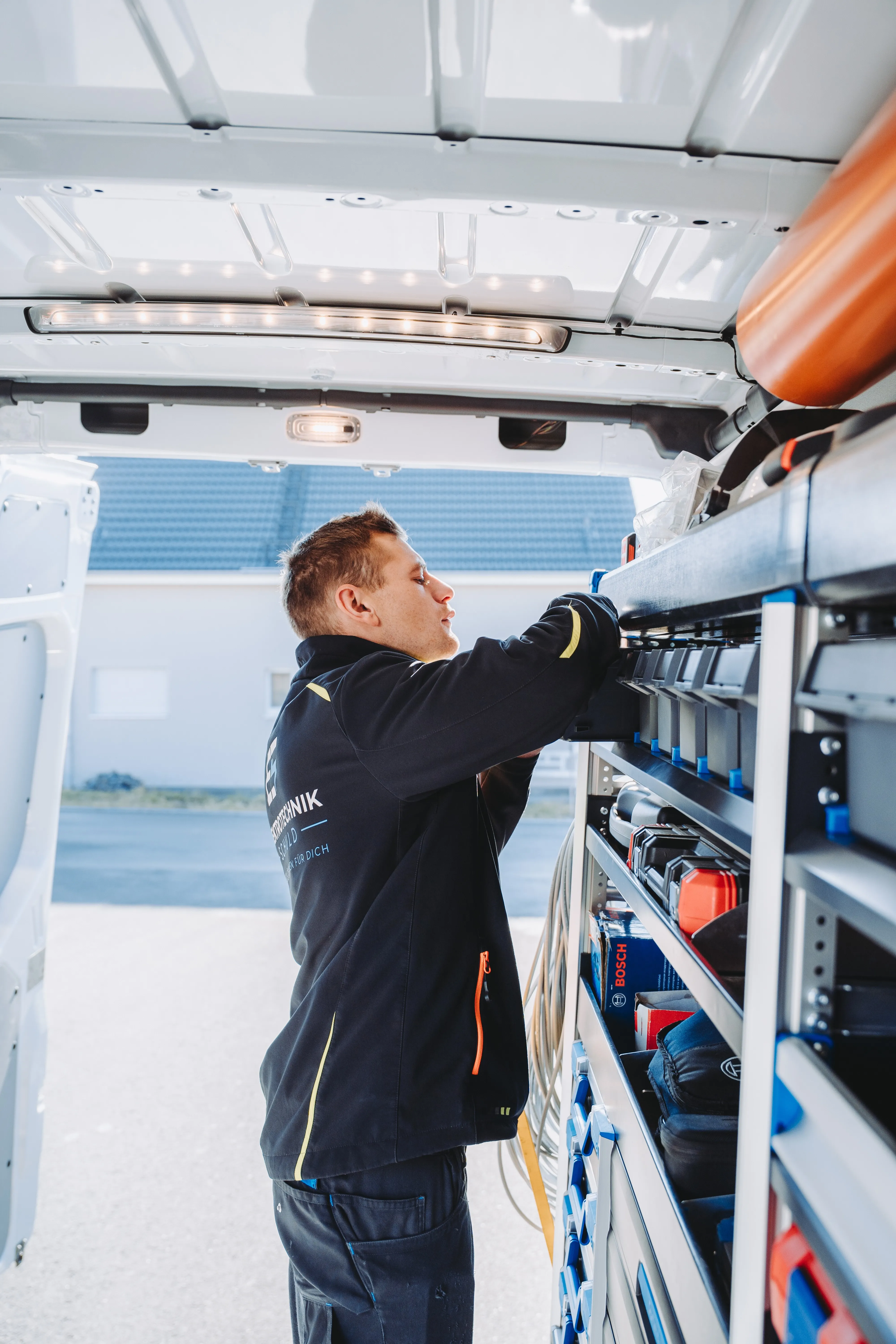 Techniker lädt Material ins Fahrzeug – mobile Einsatzbereitschaft von Elektro Schuld