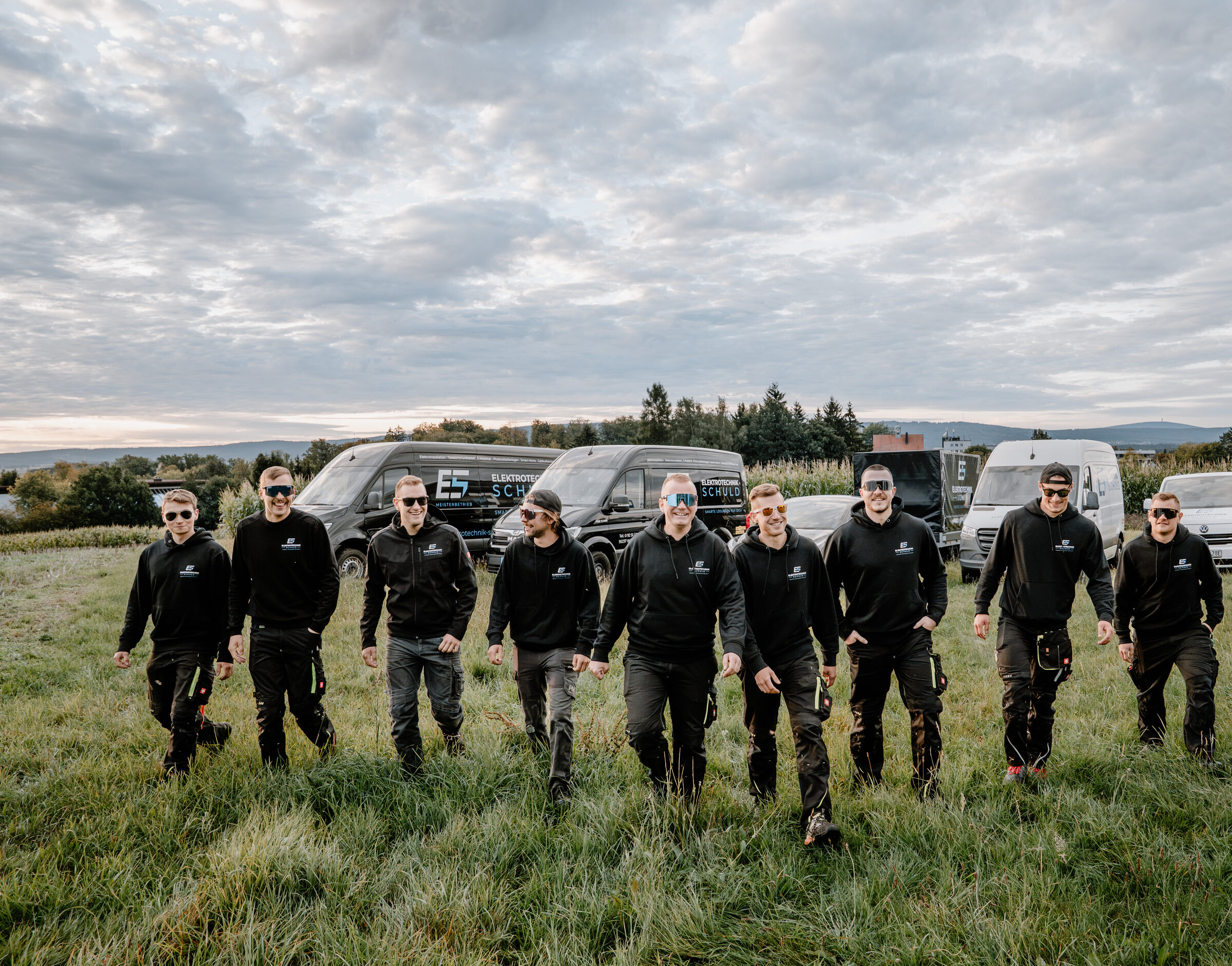 Team von Elektrotechnik Schuld vor den Firmenfahrzeugen