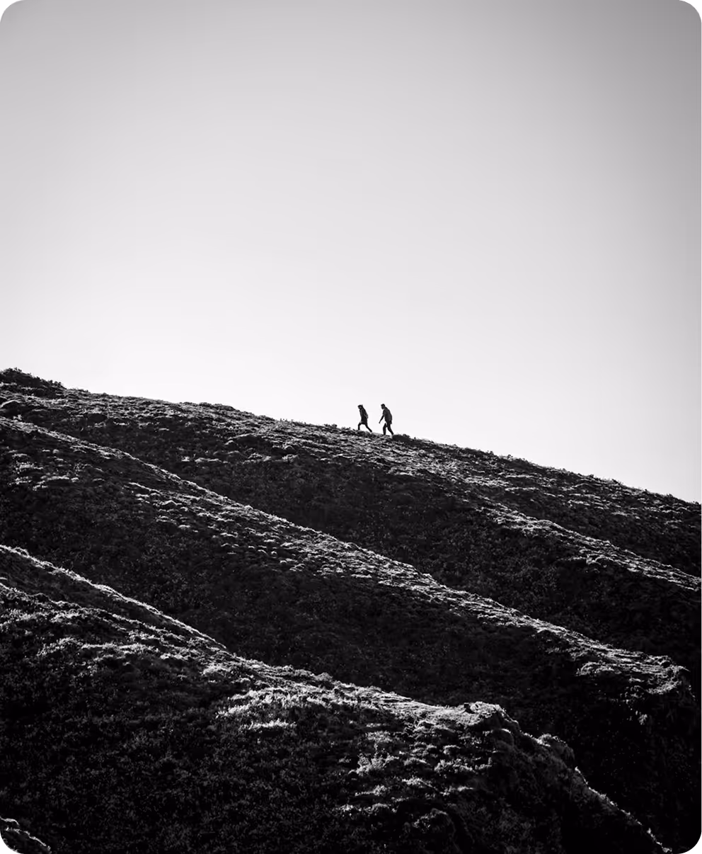 A couple of people that are standing on a hill.
