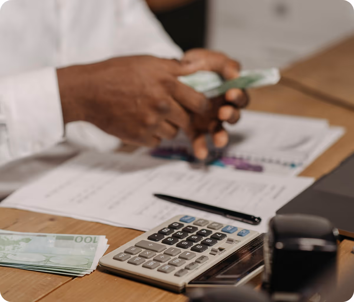 A person sitting at a desk with a calculator and money.