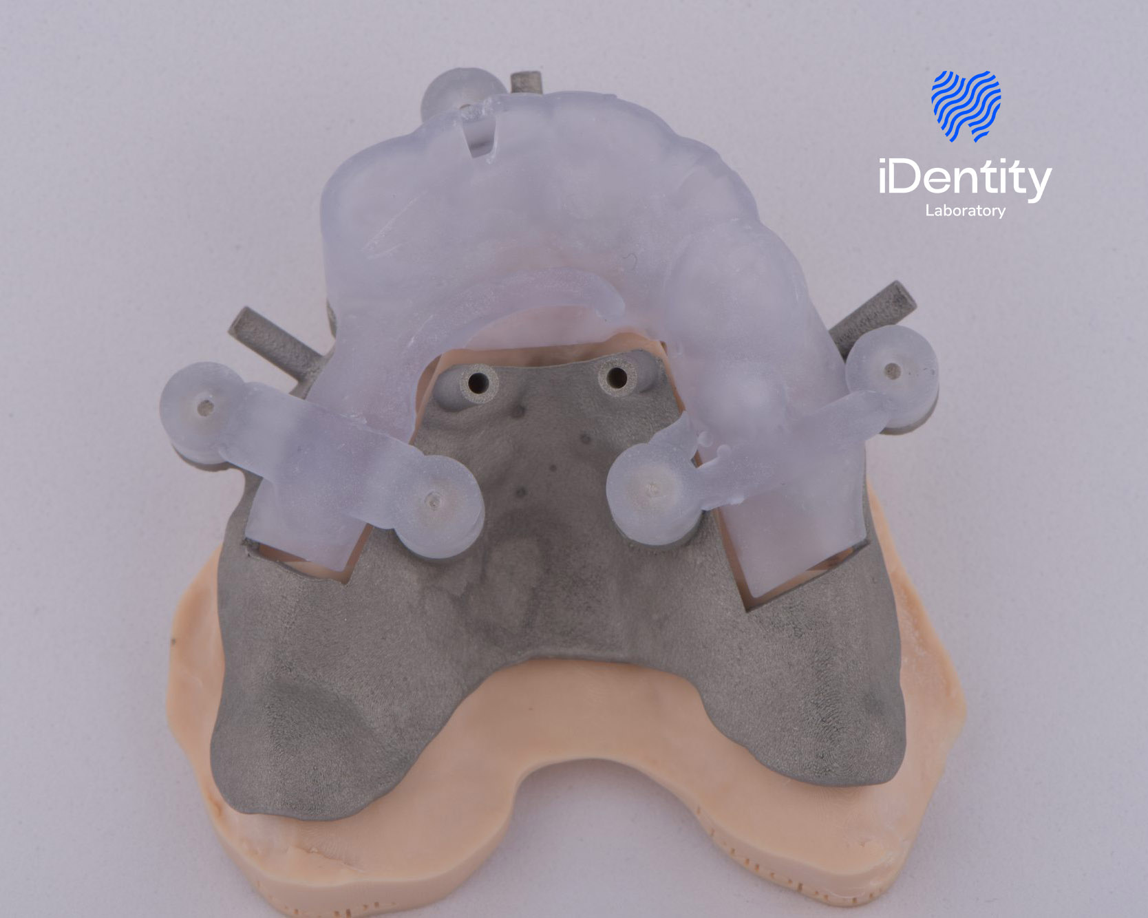 Dental implant surgical guide made of translucent plastic placed on a gray and beige dental model base.