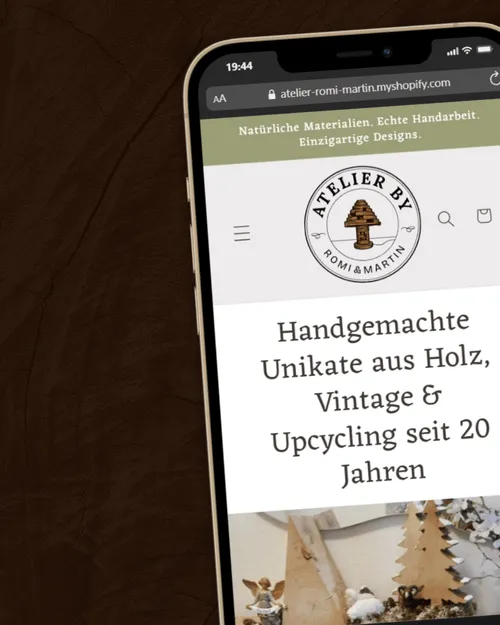 Smartphone zeigt Webseite von Atelier Romi & Martin mit handgemachten Holzunikaten, Vintage- und Upcycling-Produkten seit 20 Jahren.
