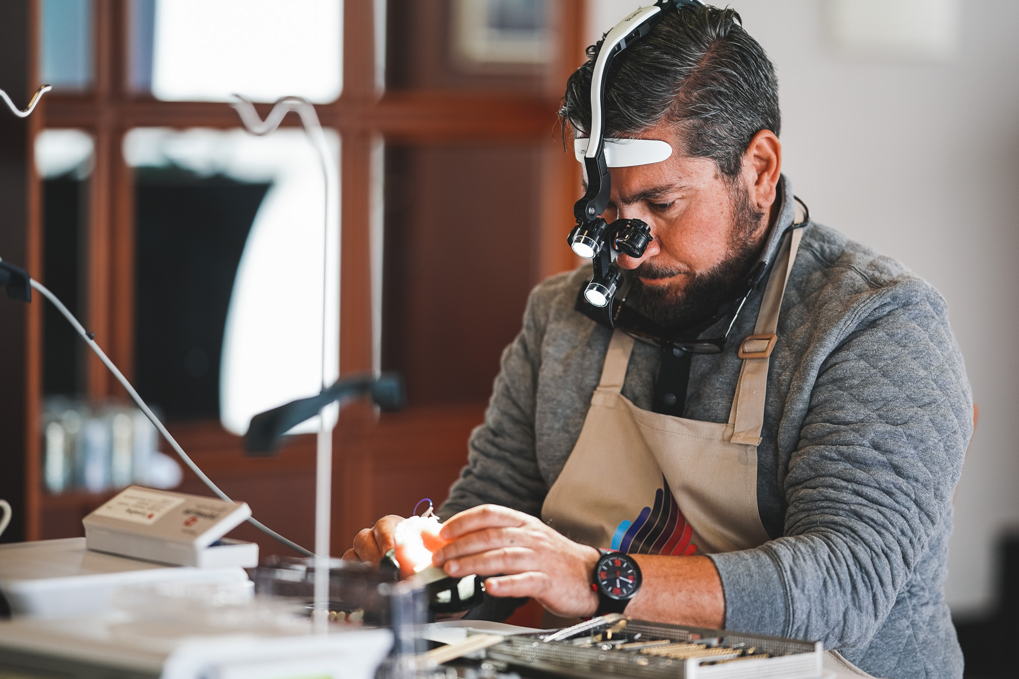 MAXI Hybrid course attendee wearing surgical loupes performing hands-on training work at a workstation.