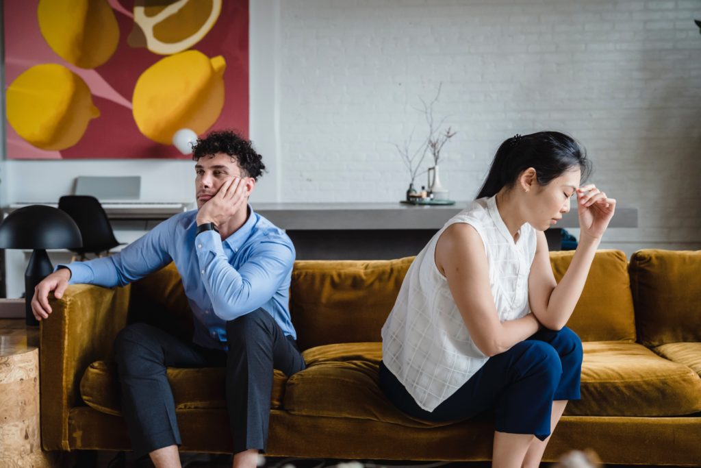 unhappy couple sitting on a sofa after cheating