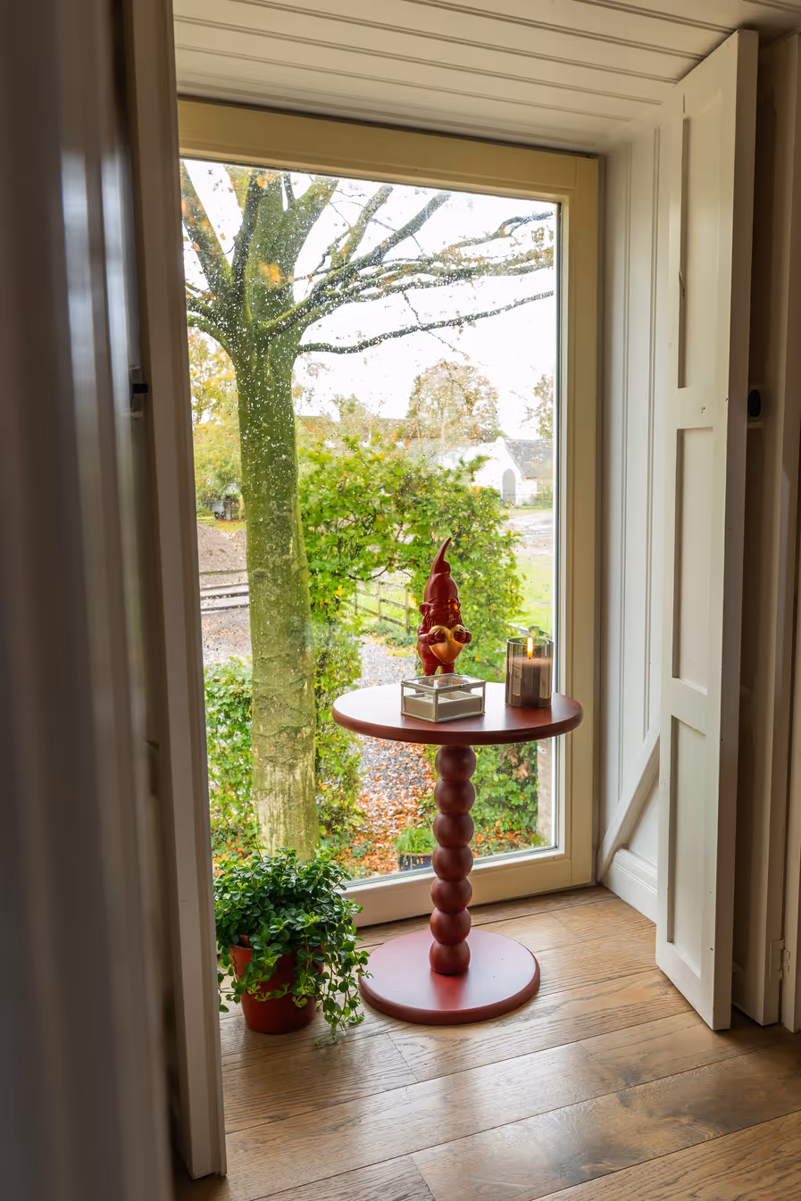 Rond tafeltje met decoratie voor raam met uitzicht op tuin