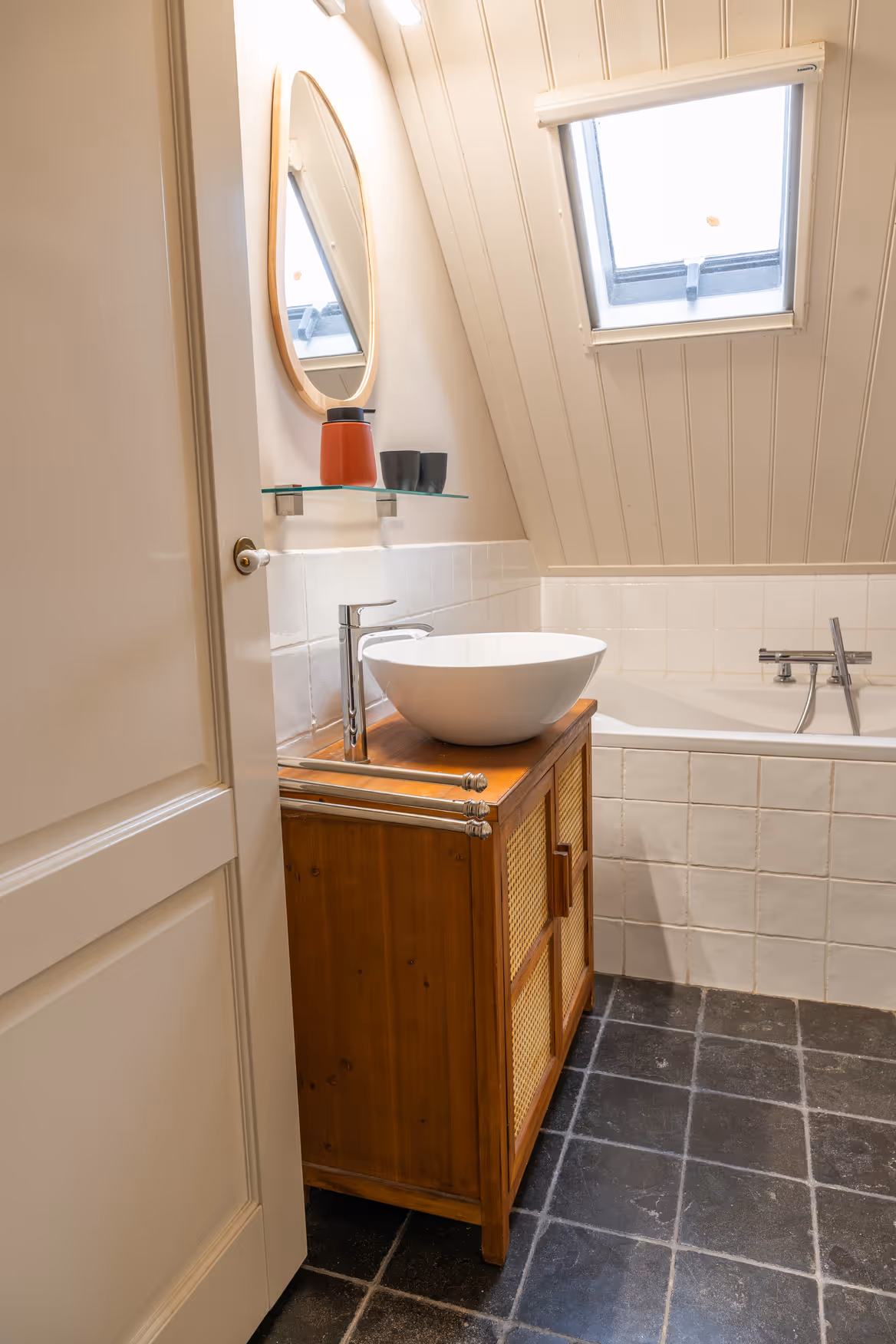 Badkamer met houten wastafelmeubel en witte betegeling