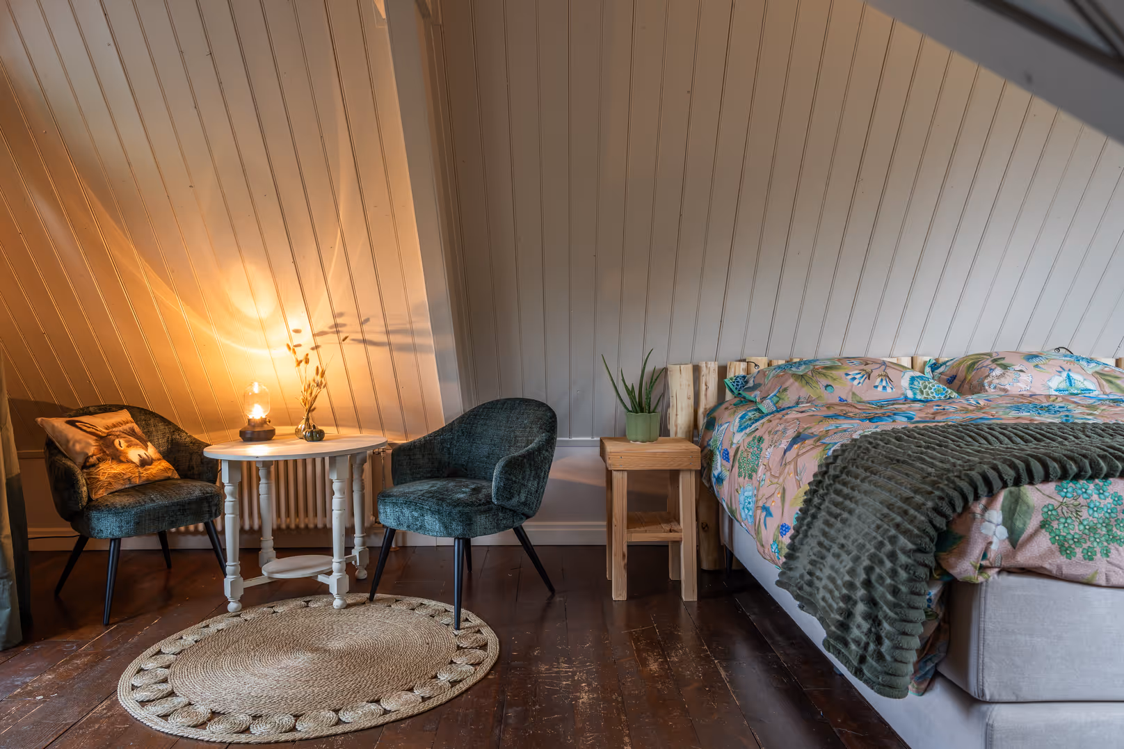 Ruime kamer met houten vloer en groen dekbed