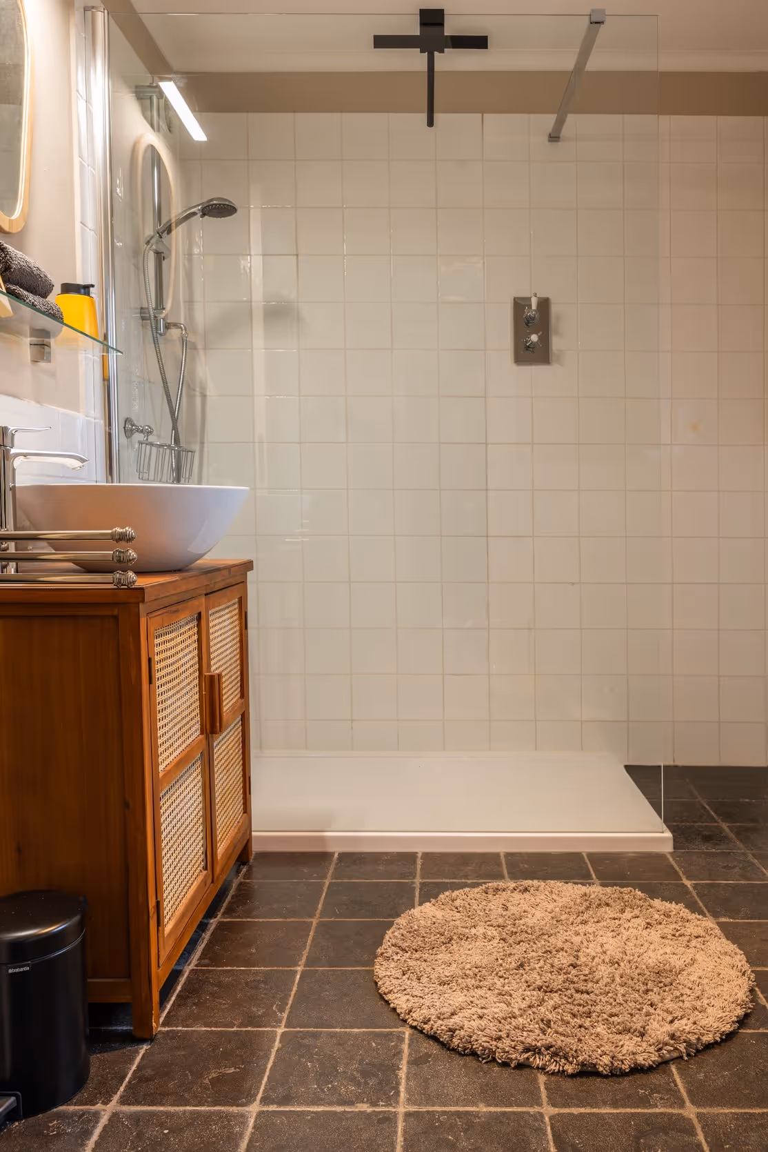 Badkamer met wastafel, regendouche en witte tegels