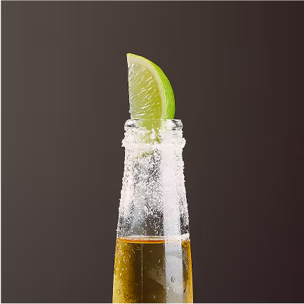 Bottiglia di birra con fetta di lime sul bordo su sfondo scuro.