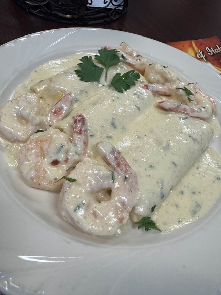 A plate of shrimp in creamy sauce, garnished with green herbs.