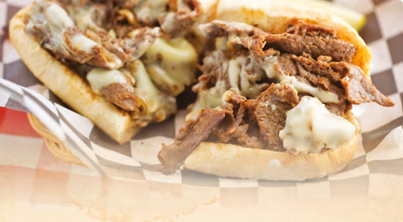 Philly cheesesteak sandwich with melted cheese and sliced beef on a hoagie roll.