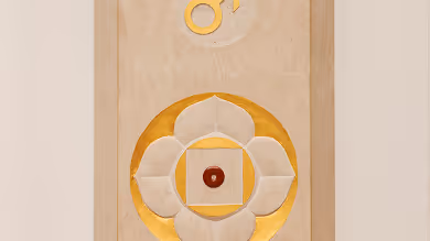 Abstraktes Kunstwerk mit einem kreisförmigen floralen Muster in Gold- und Beigetönen an einer Wand.