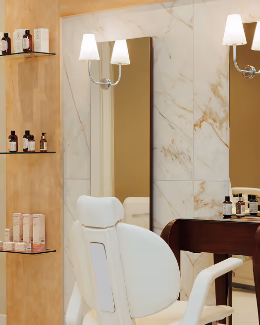 Moderner Friseursalon mit weißem Friseurstuhl vor Spiegel und Regalen mit Haarpflegeprodukten.