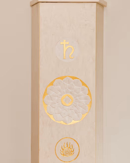 Heller, vertikaler dekorativer Pfeiler mit goldenen Symbolen und einer weißen Blütenornament-Verzierung in der Mitte.