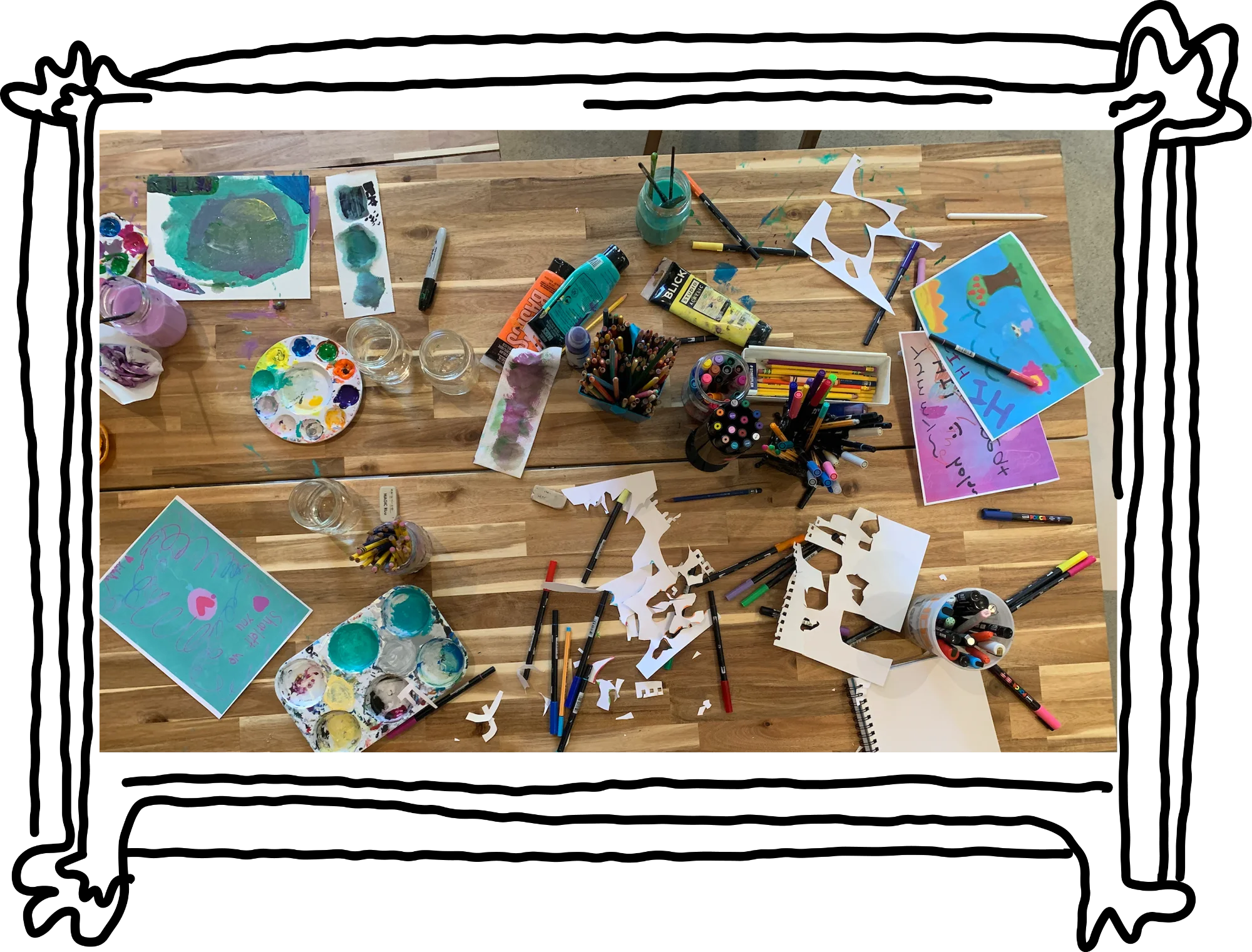 Photo of messy art supplies on a wooden table.