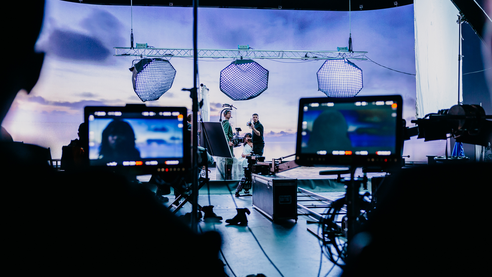 Film crew working on a set with large studio lights and monitors displaying a close-up of an actor.