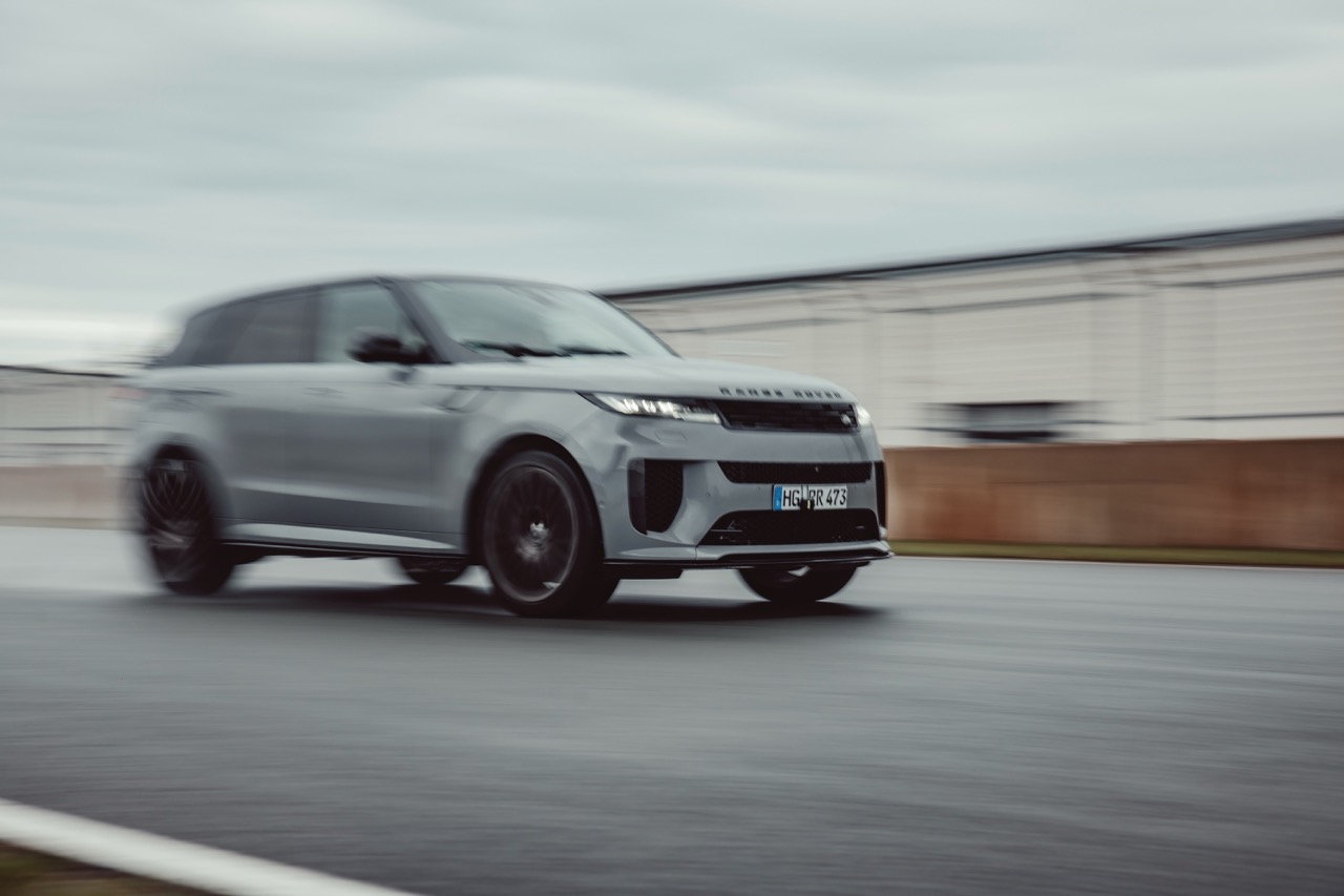Silver Range Rover SUV driving quickly on a wet road with motion blur.