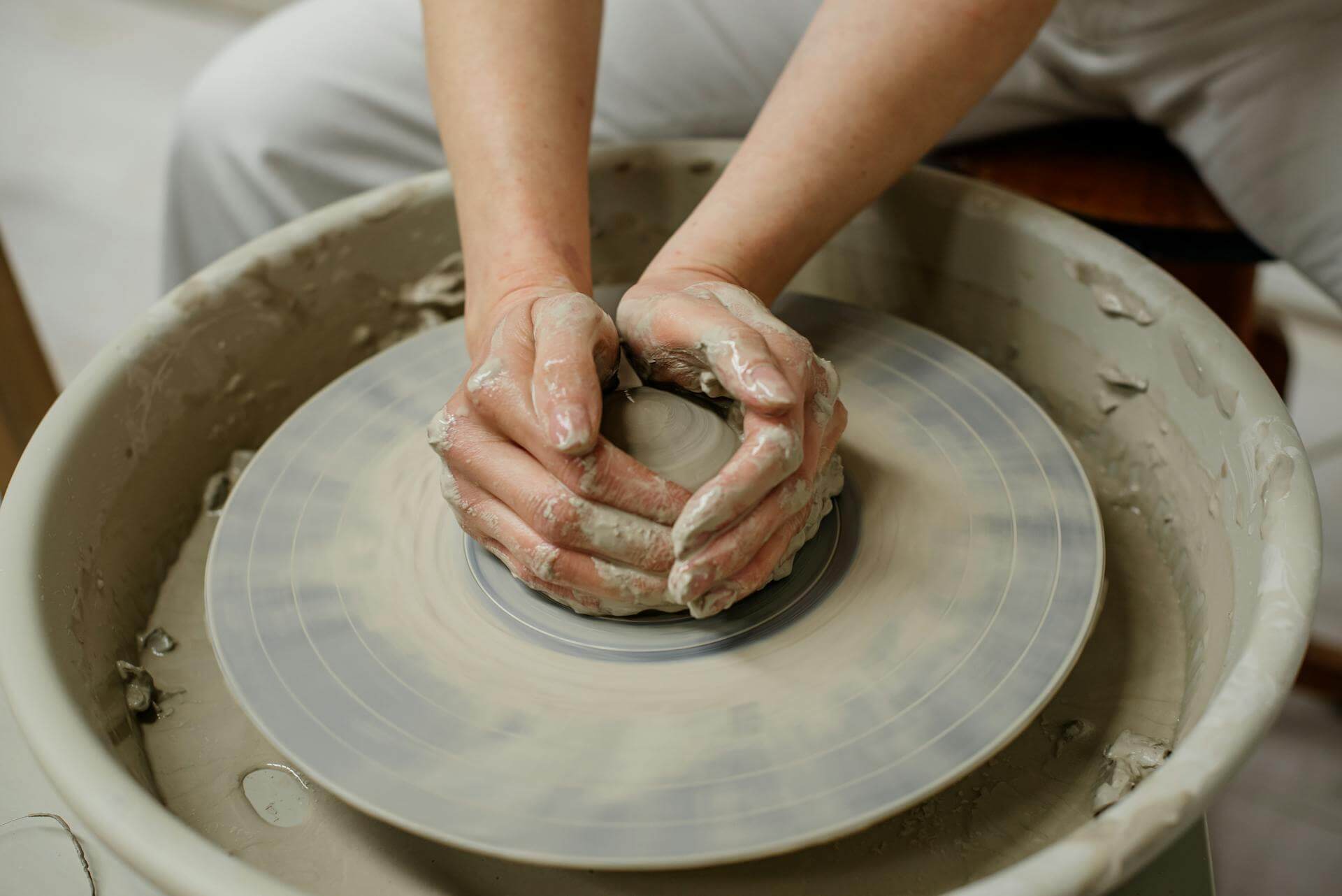 Hands shaping clay on a spinning pottery wheel.