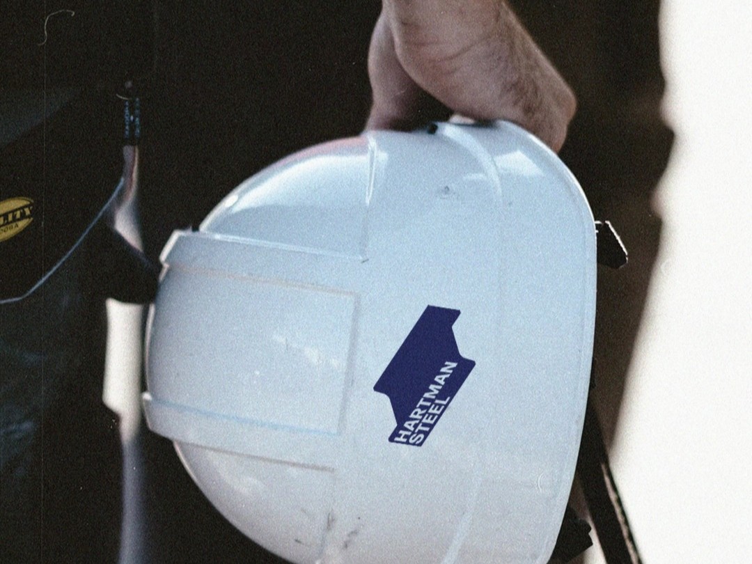 Person holding hard hat with Hartman Steel Logo