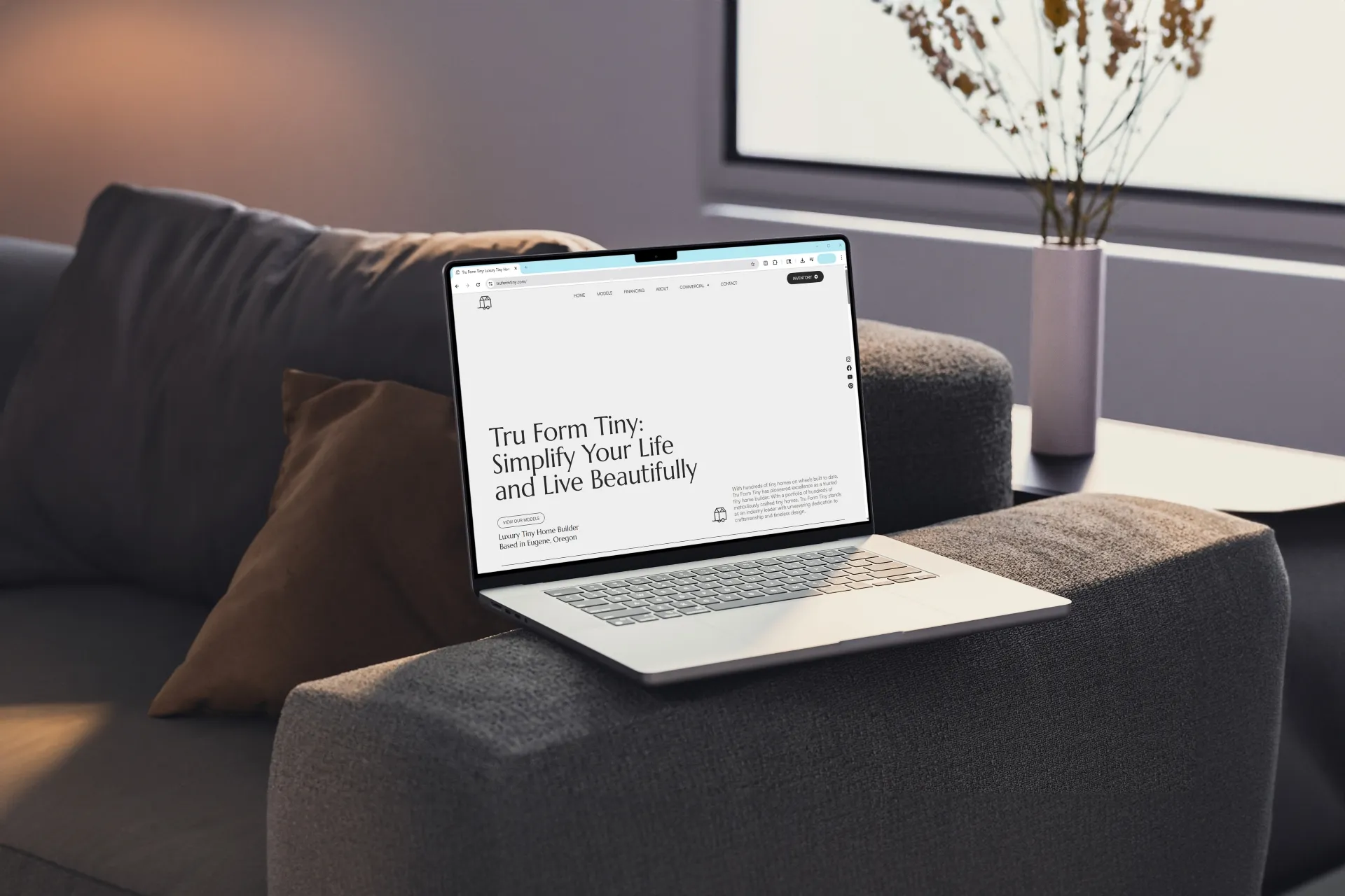 Laptop displaying Tru Form Tiny website with the headline 'Simplify Your Life and Live Beautifully' on a gray couch armrest.