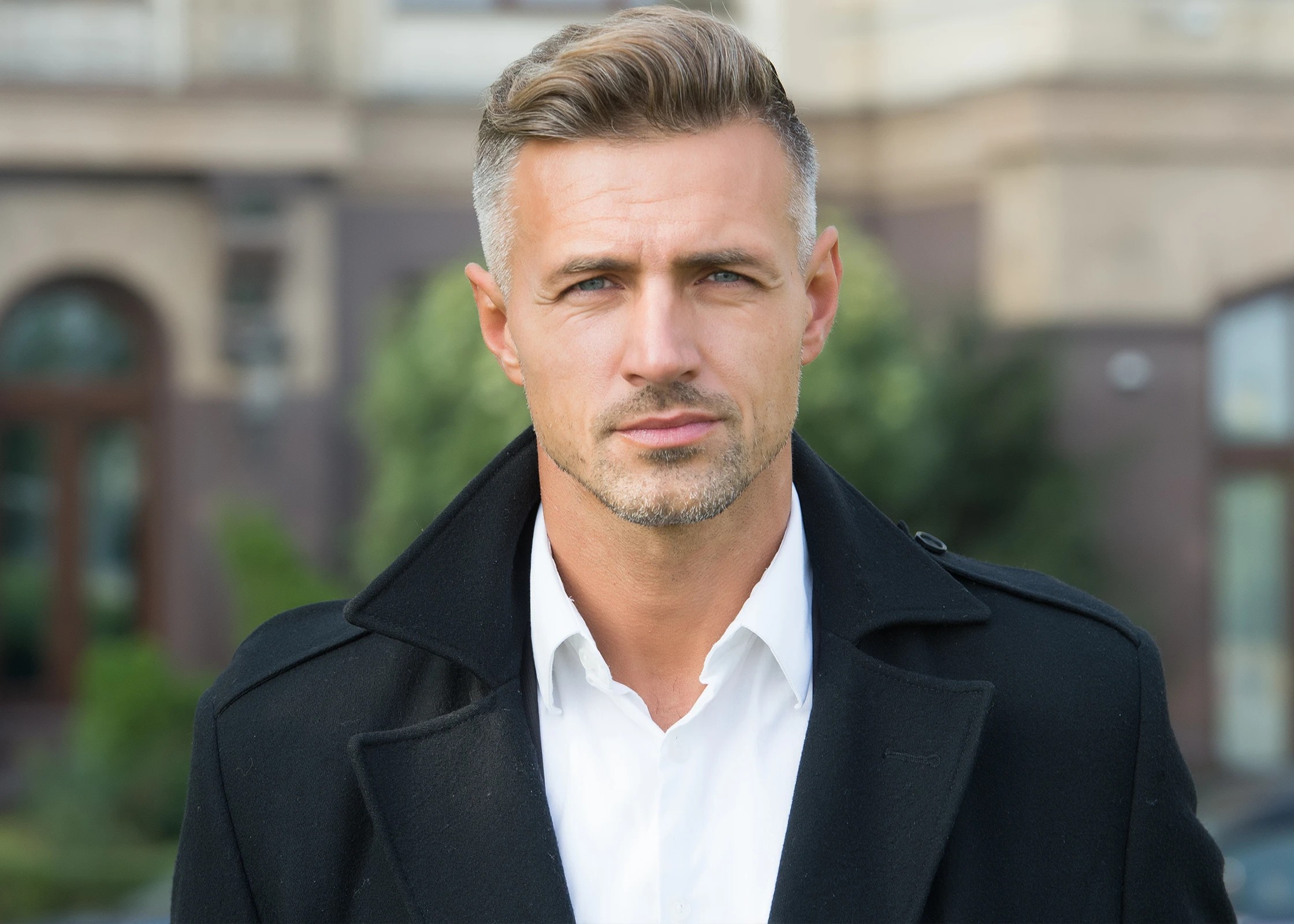 A man wearing a black coat and a white shirt.