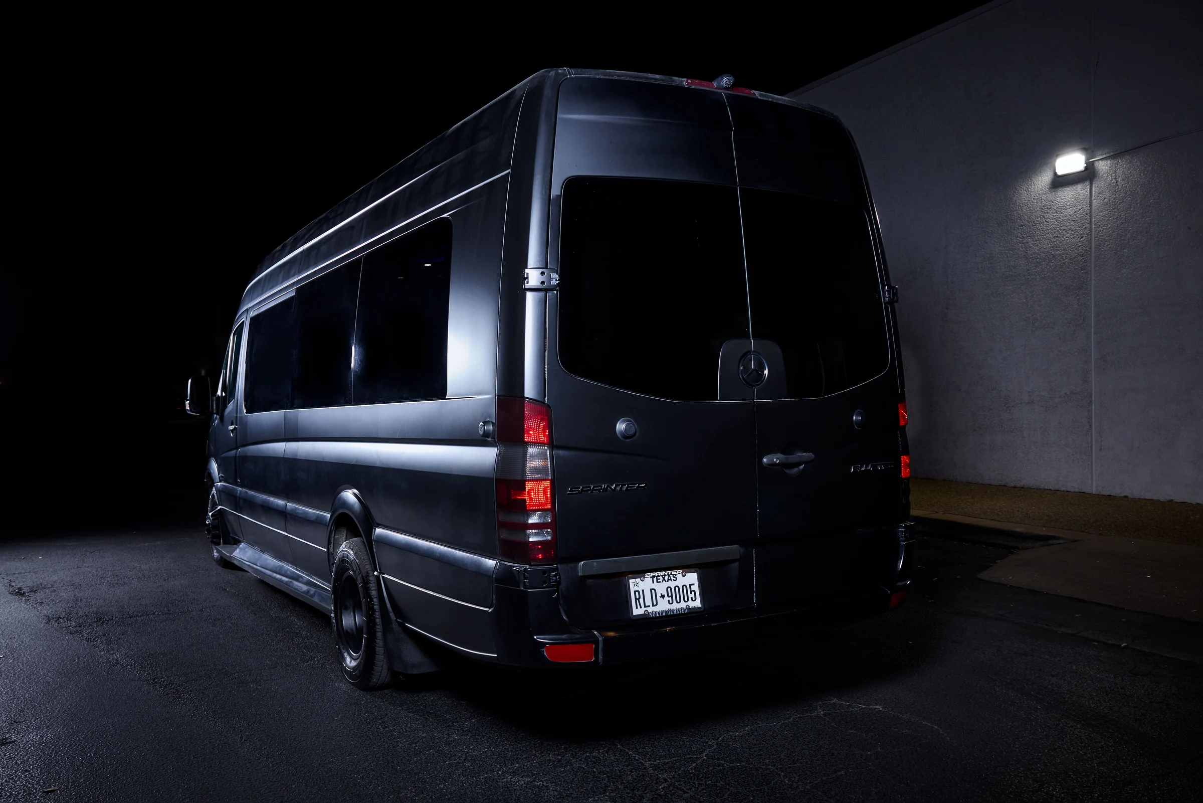 Rear view of the matte black VANTA BLK Mercedes-Benz Sprinter at night