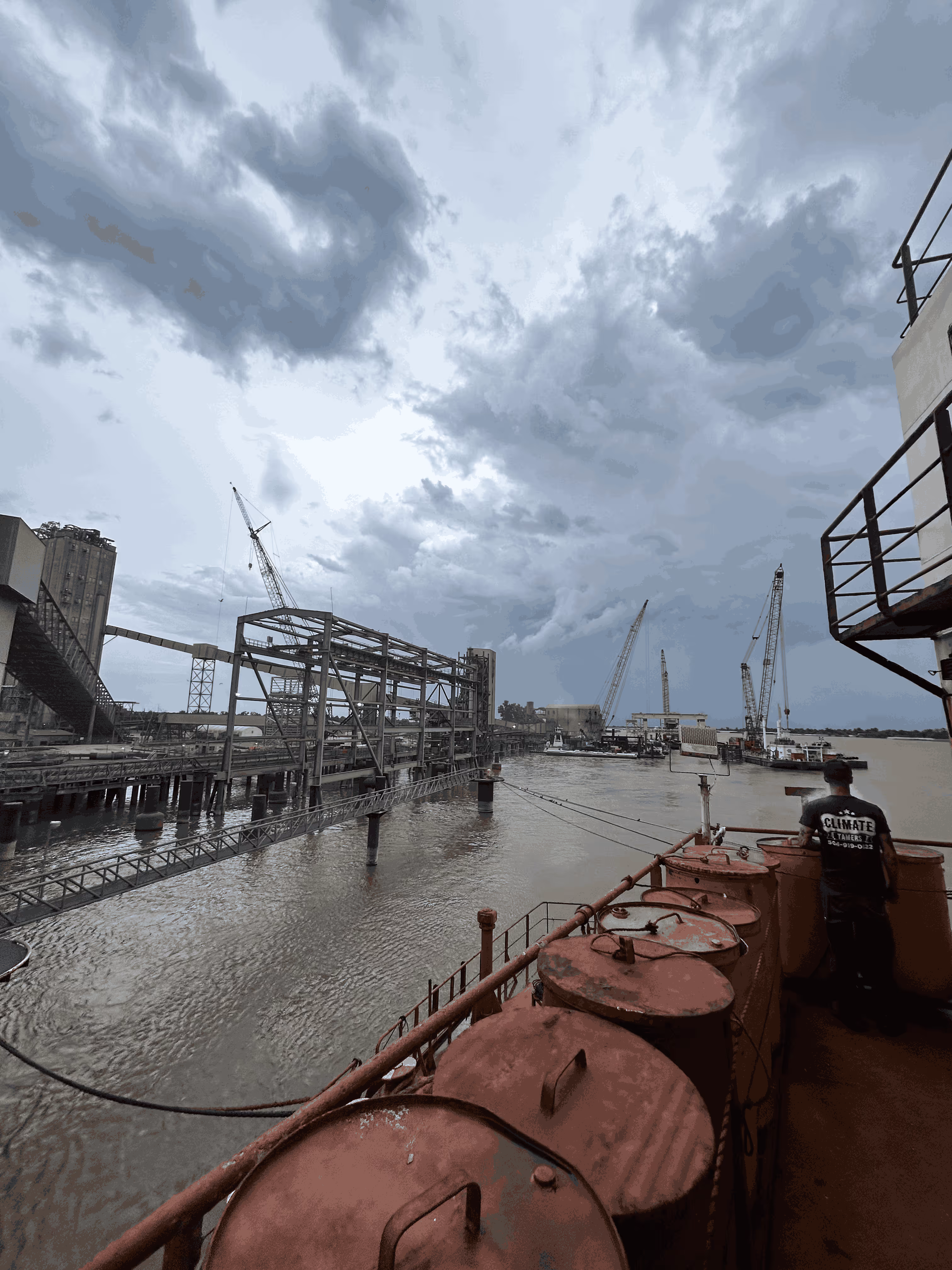 A large body of water next to a bridge under a cloudy sky.