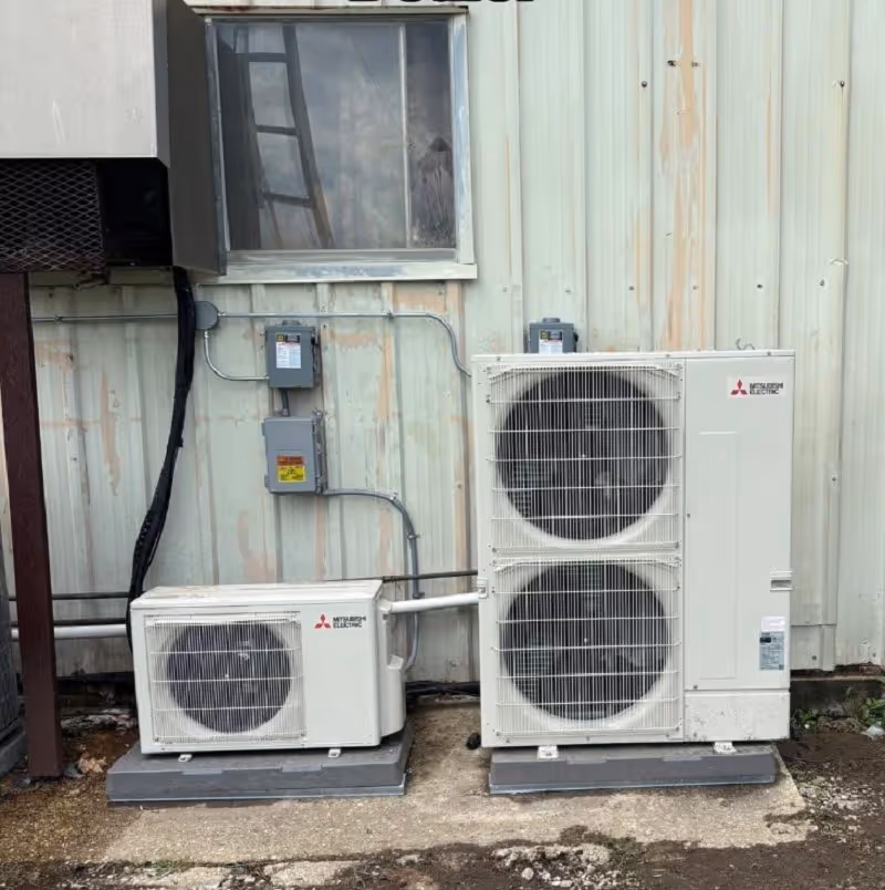 A couple of air conditioners sitting next to a building.