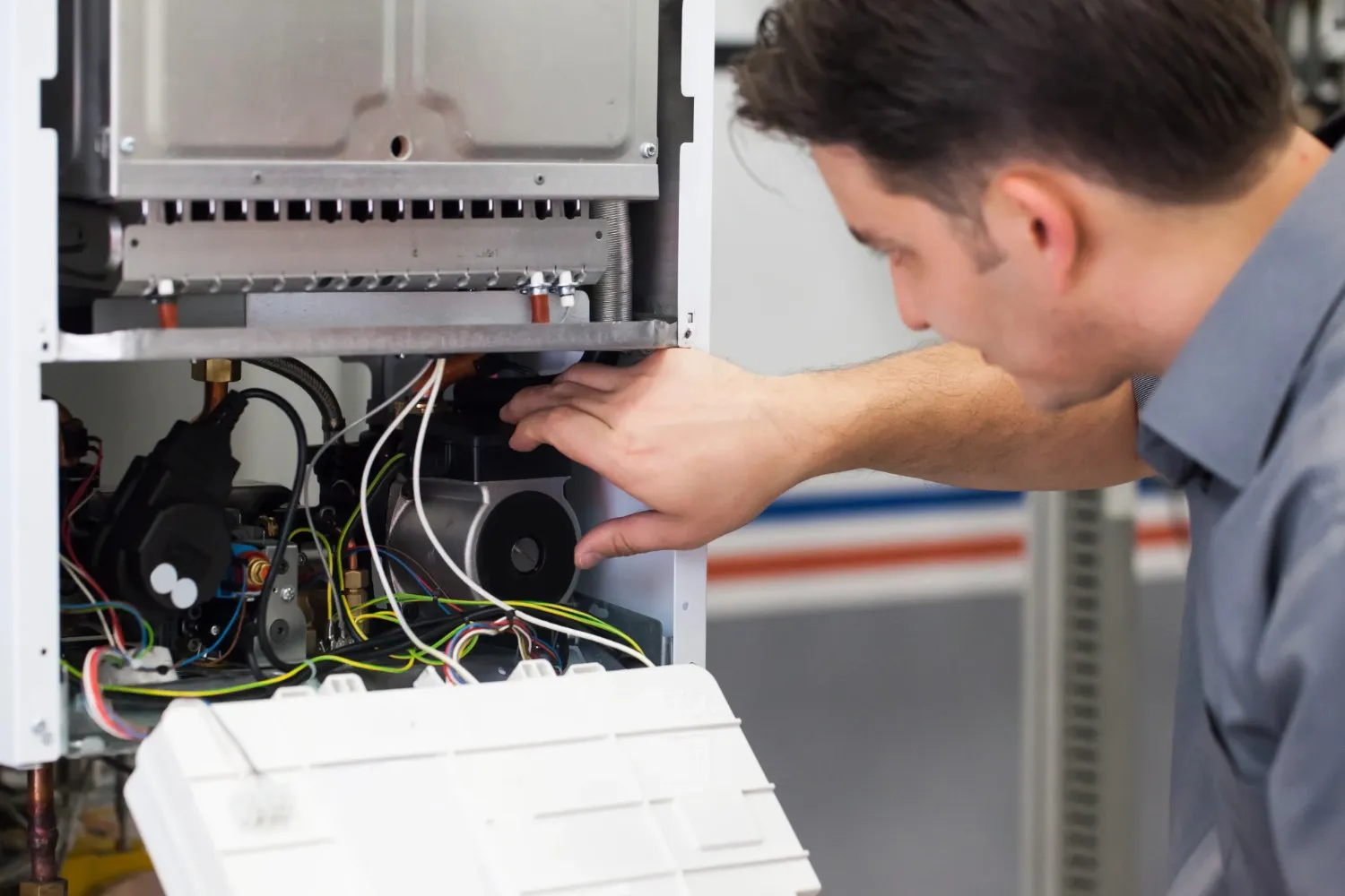 A technician is performing service or maintenance on the internal components of a furnace unit.