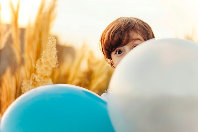 Small kid hiding behind balloon