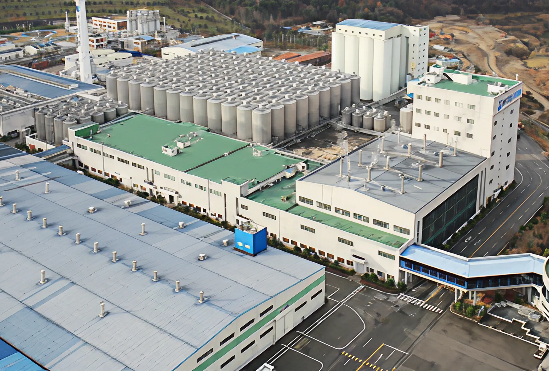 Aerial view of industrial plant with silver tanks and green roof