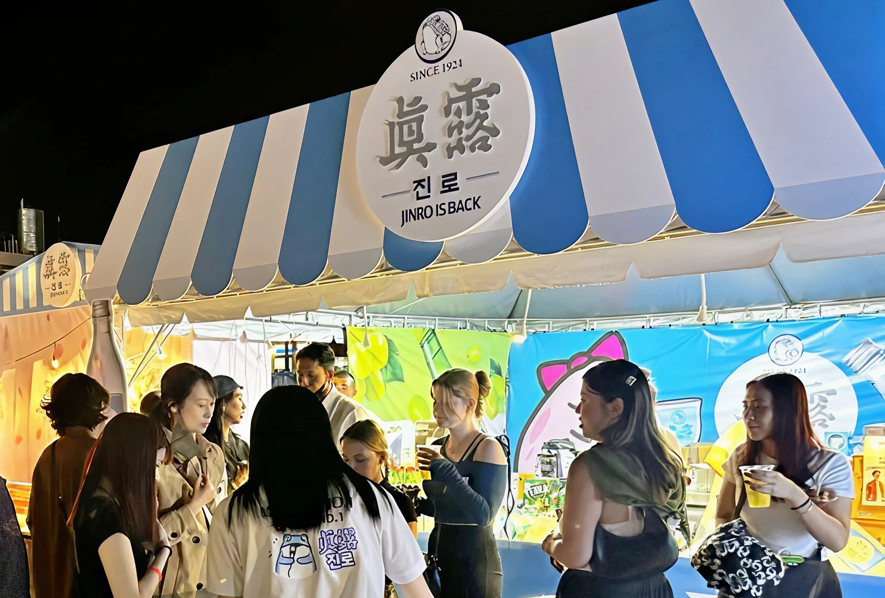 People gathered at the JINRO booth at night.