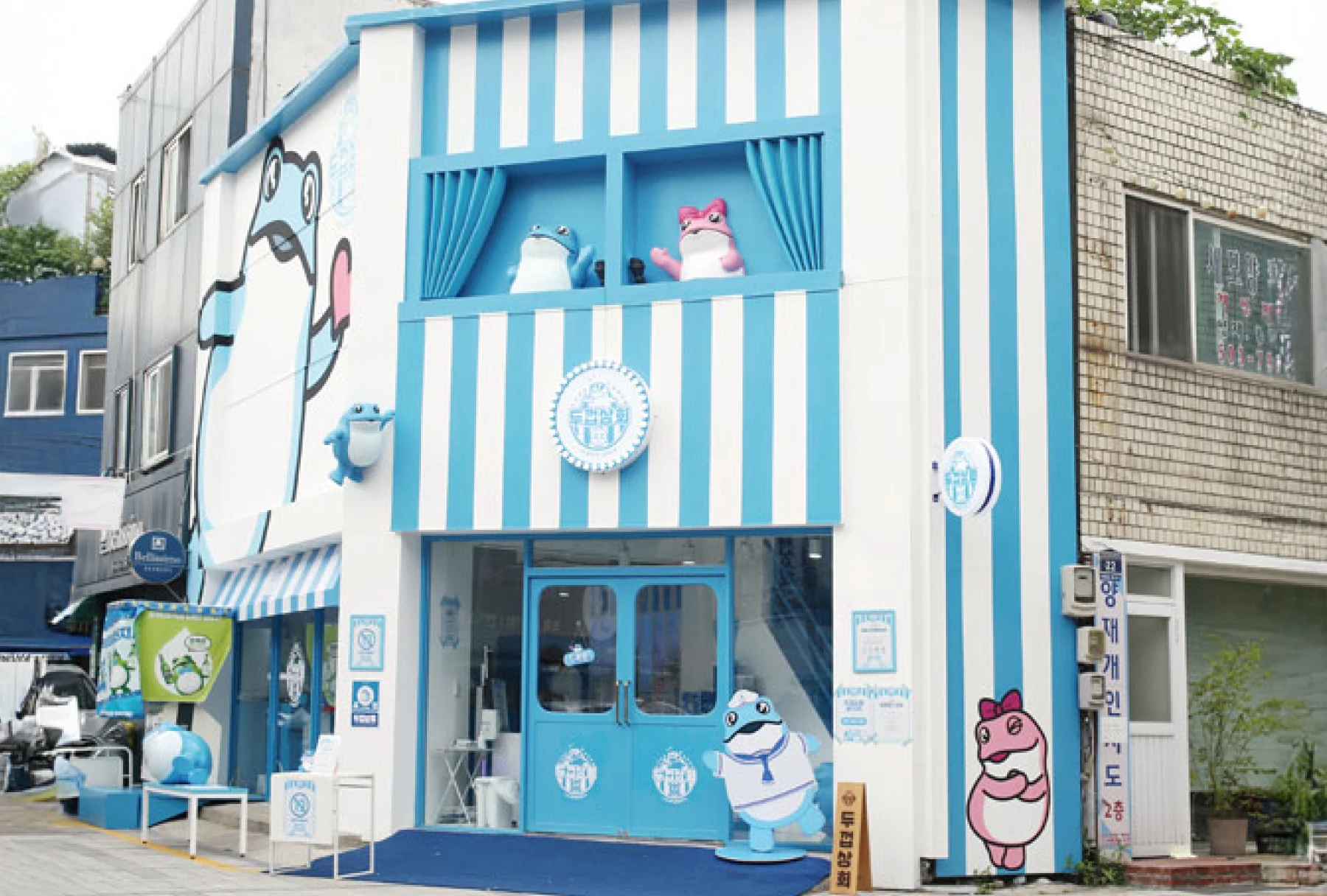 Blue and white JINRO-themed building with frog mascots.
