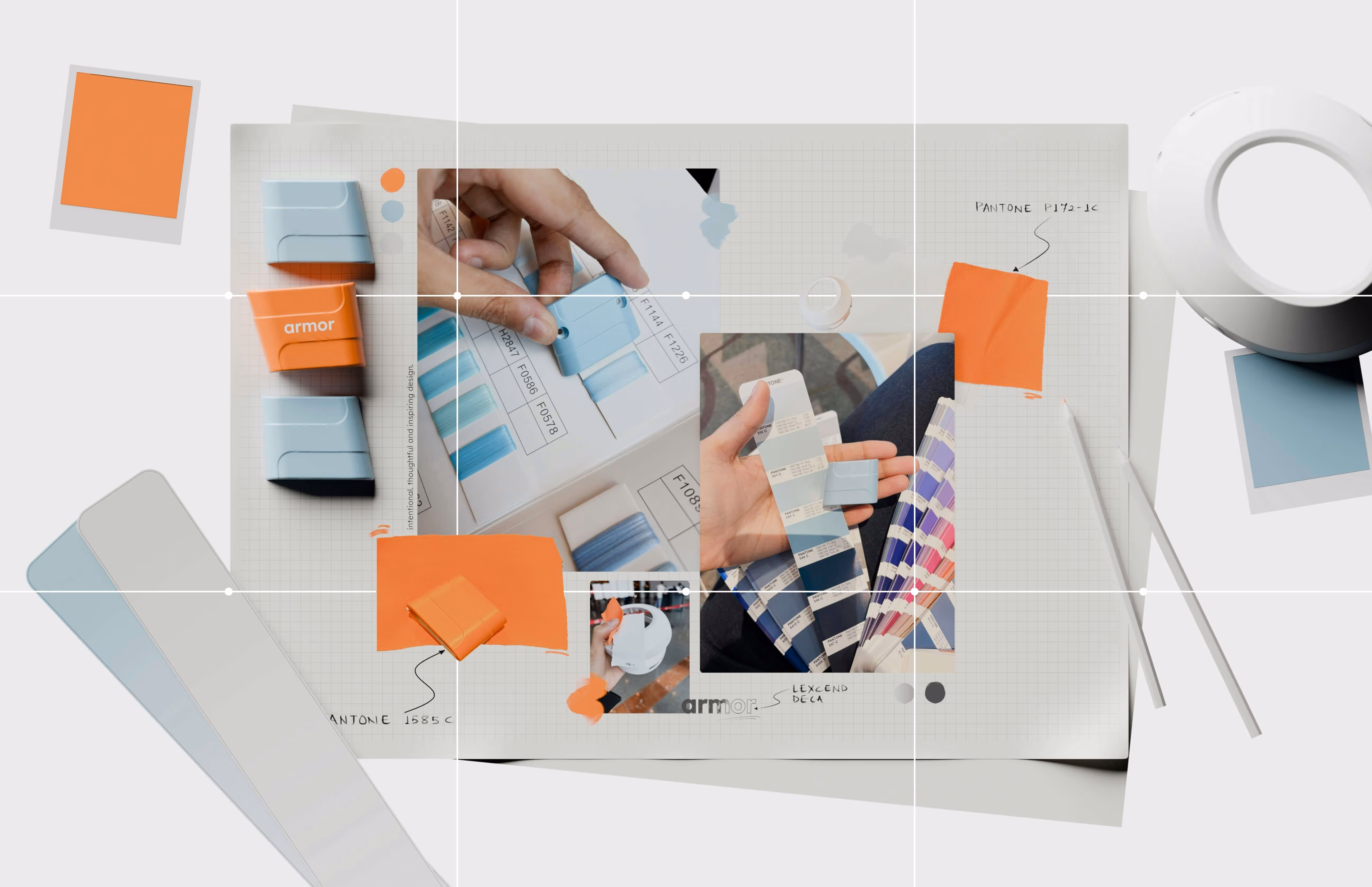 Desk with color swatches, design samples, and a hand holding a blue color chip labeled 'armor' on a grid paper background with Pantone color notes.