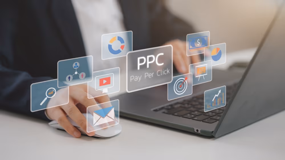 Person using laptop and mouse with floating digital icons related to Pay Per Click marketing.