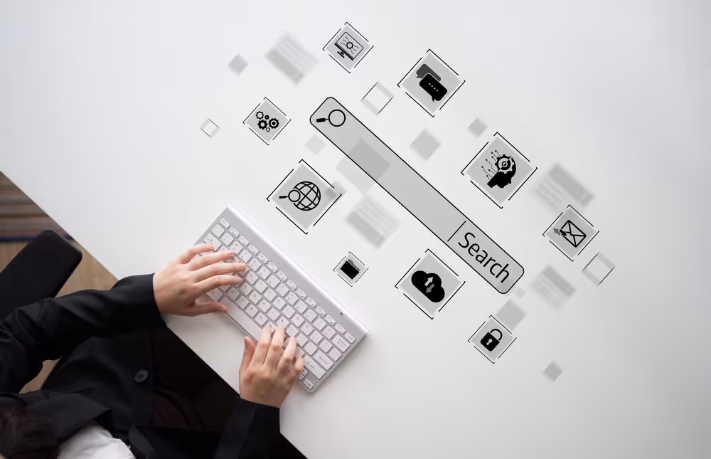Person typing on a wireless keyboard with floating digital icons and a search bar labeled 'Search' above the keyboard.
