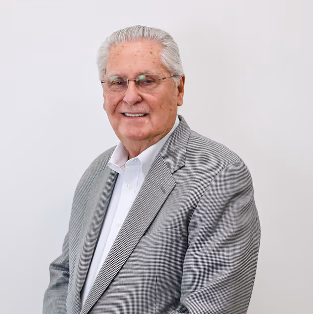 Paul Philips wearing glasses and a gray checkered blazer smiling against a white background.