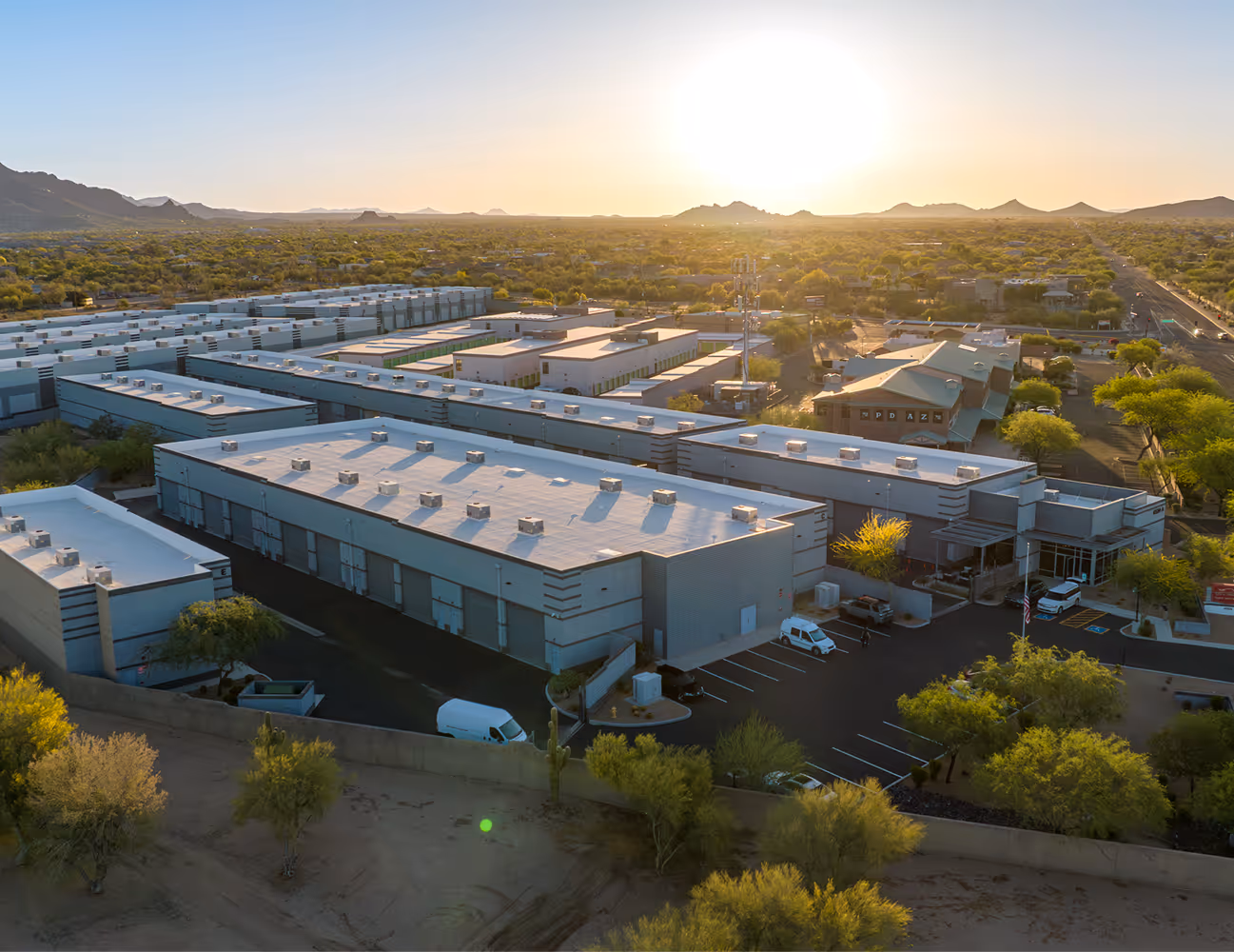 Aerial view of a large commercial building complex at sunset surrounded by desert landscape.