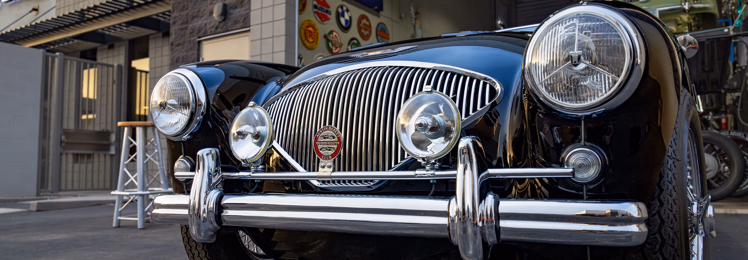 Front view close-up of a classic black Austin-Healey car with chrome grille and round headlights.