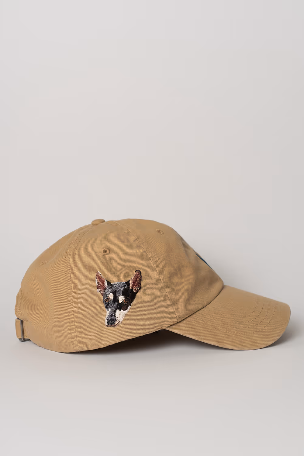 Tan baseball cap with an embroidered dog face on the side.
