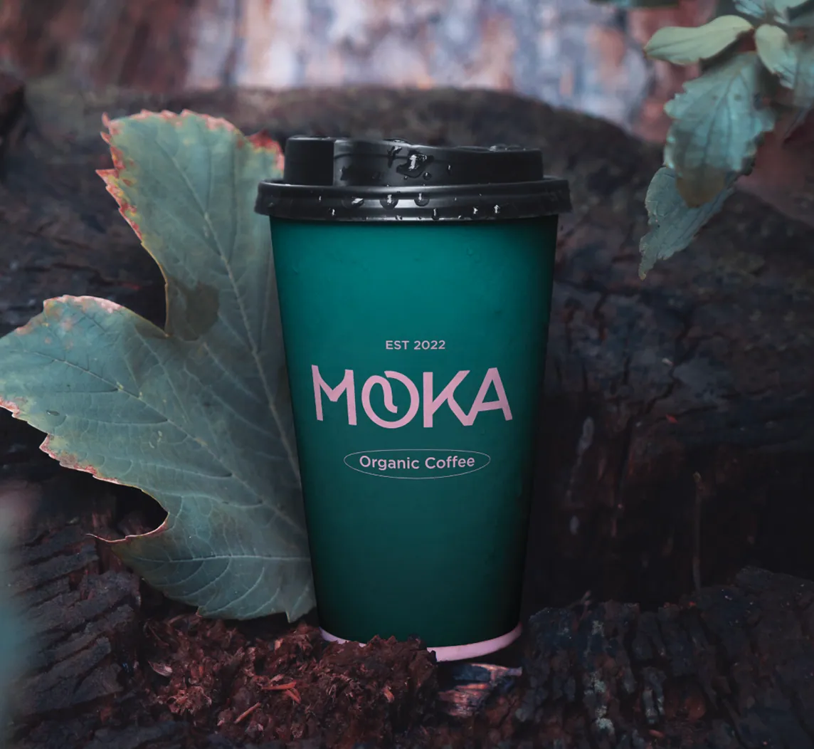 Gobelet personnalisé du projet Moka, marque de café bio et éthique, mettant en avant un design écologique avec logo rose sur fond vert profond, symbole d’un engagement durable.