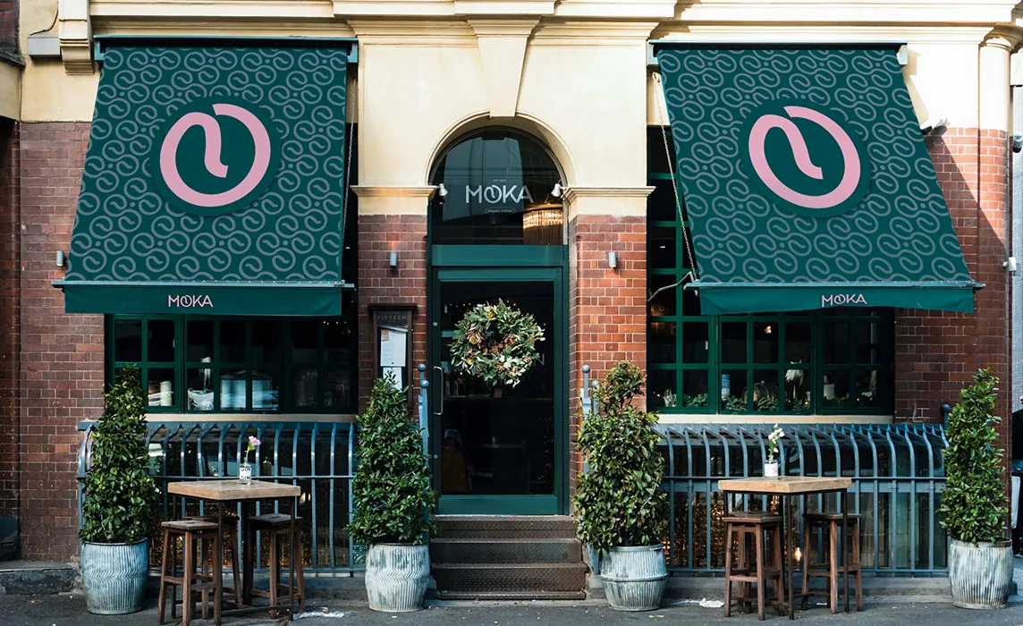 Devanture du café Moka, marque de café bio et éthique, avec enseignes et auvents personnalisés affichant le logo rose sur fond vert, illustrant une identité visuelle élégante et durable.