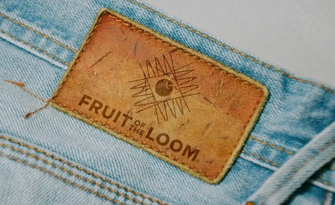 Étiquette en cuir sur jean pour le projet de rebranding Fruit of the Loom, mettant en avant le nouveau logo gravé et l’esthétique vintage de la marque de vêtements revisité.
