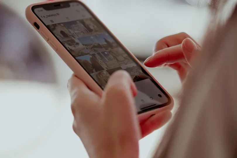 Mains tenant un smartphone pour consulter les réseaux sociaux